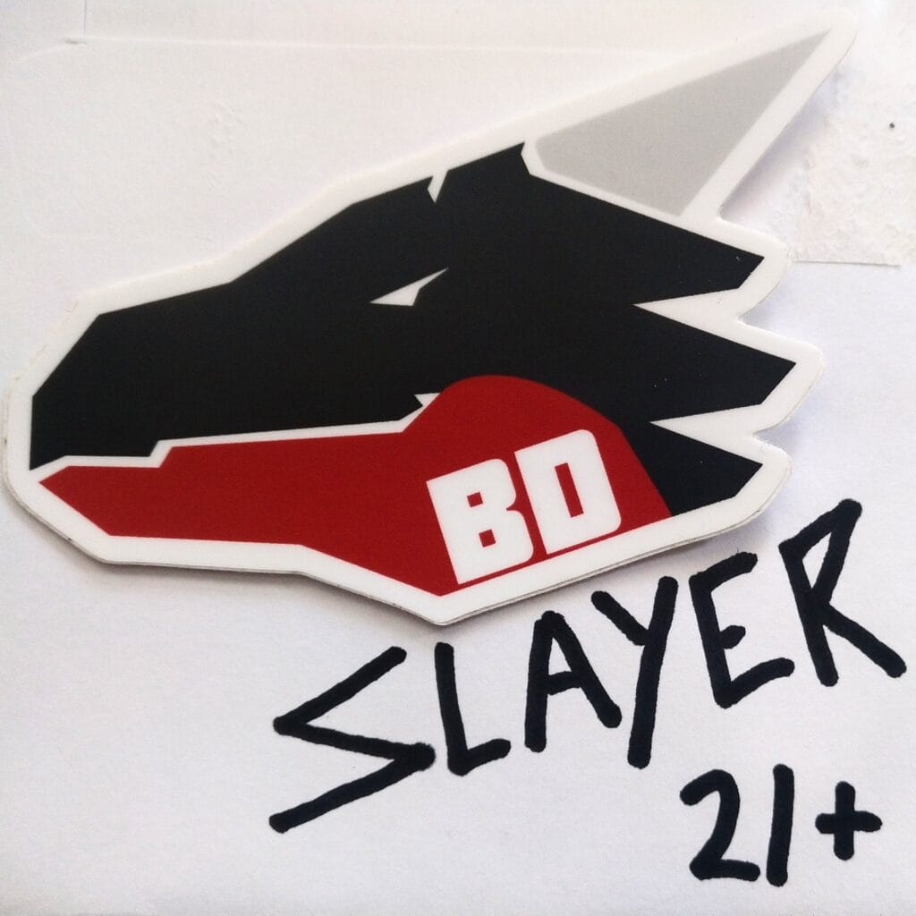Close-up of a sticker with a black background and red and white graphic elements on a white surface, partially cropped.