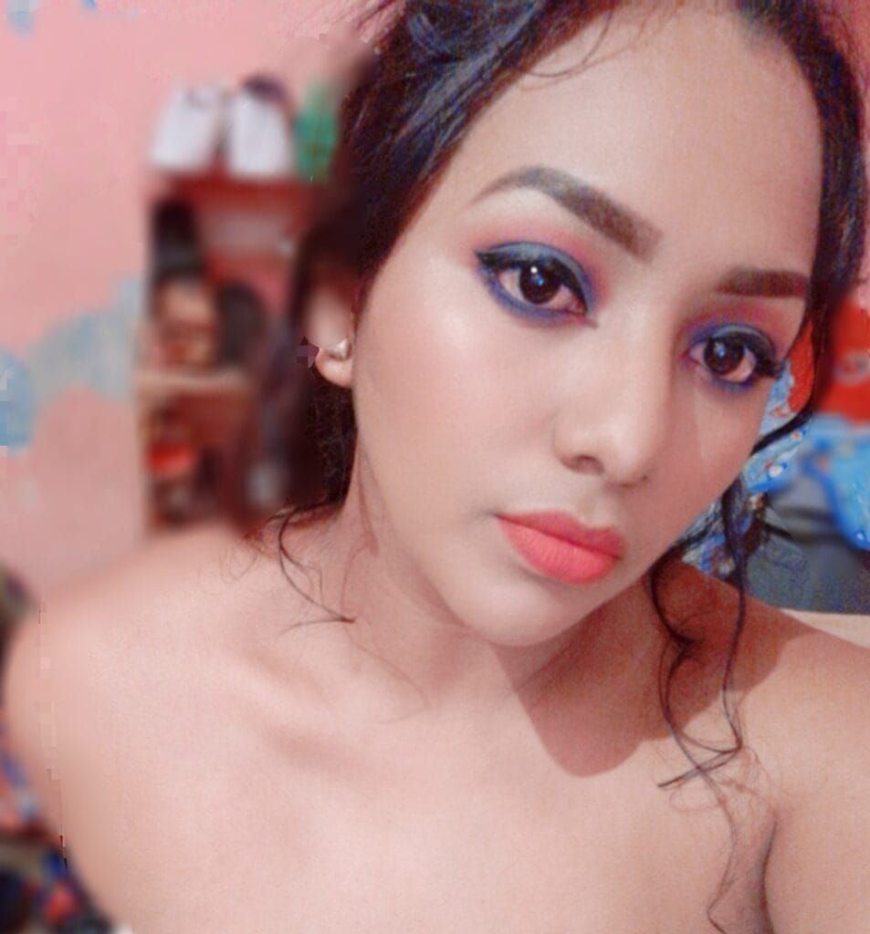 Close-up of a woman's face showing bold eye makeup and pink lips with a blurred background.