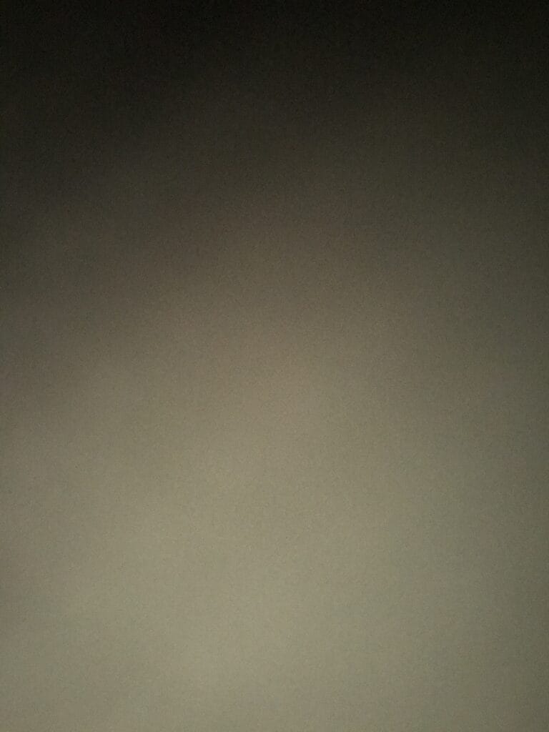 Solid gradient wall transitioning from dark gray at the top to light beige at the bottom.